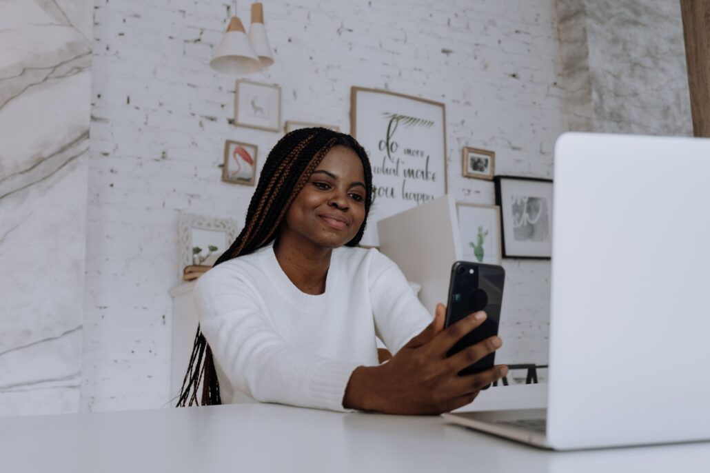 woman looking at her phone and laptop while on a video call